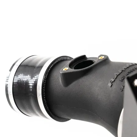 Close-up of the RamAir Proram intake kit for the Toyota GR Yaris. The kit consists of a black intake pipe with silver clamps and a connector. A white, neutral background is visible in the background.