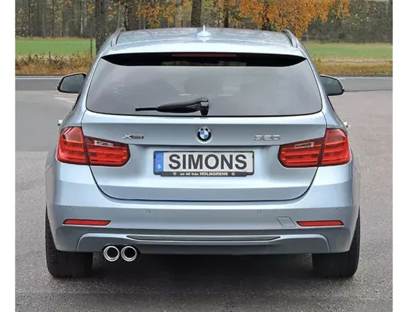 Rear view of a silver BMW F30 Touring. License plate with "Simons" lettering. The Simons stainless steel sports exhaust system with 2 tailpipes (80mm) is visible at the bottom left. Red rear lights and bumper visible.