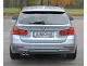 Rear view of a silver BMW F30 Touring. License plate with "Simons" lettering. The Simons stainless steel sports exhaust system with 2 tailpipes (80mm) is visible at the bottom left. Red rear lights and bumper visible.