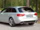 Rear view of a silver Audi A4 Avant/Kombi (B8) with duplex sports muffler from Simons. The tailpipes, each 1x100mm, are mounted on the left and right. The license plate bears the name "Simons". The car is parked on a paved road in front of trees.